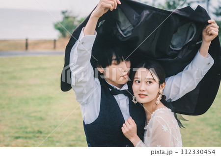 屋外で雨の中寄り添う男女 112330454