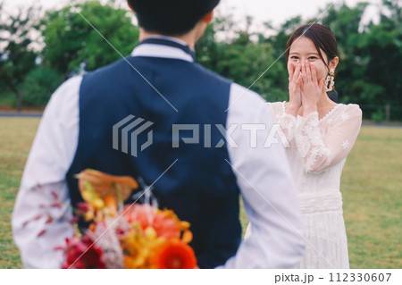 新婦に渡す花束を背中に隠している新郎 112330607