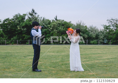 公園で新婦を撮影する新郎 112330629
