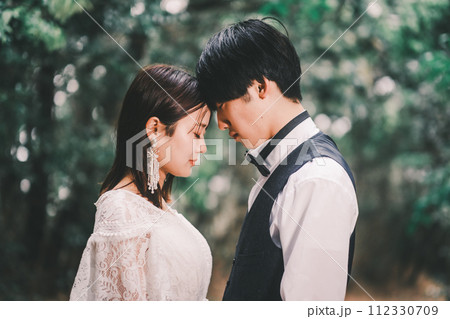 森林の中で向き合う新郎新婦 112330709
