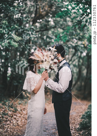 ブーケを持ち寄り添う新郎新婦 112330761