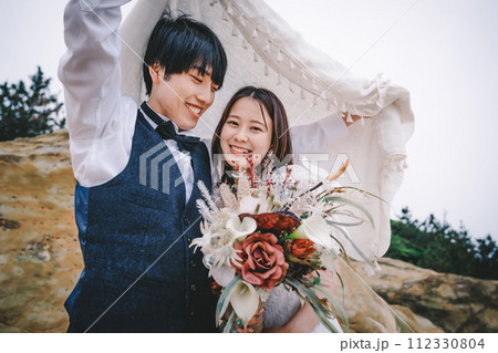 岩場で寄り添う新郎新婦 岩場で寄り添う新郎新婦 112330804