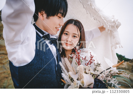 岩場で寄り添う新郎新婦 112330805