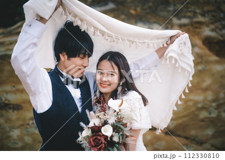岩場で寄り添う新郎新婦 112330810