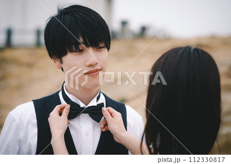 新婦にネクタイを締めてもらう新郎 112330817