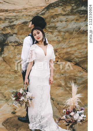 岩場で背中合わせに立つ新郎新婦 岩場で背中合わせに立つ新郎新婦 112330904