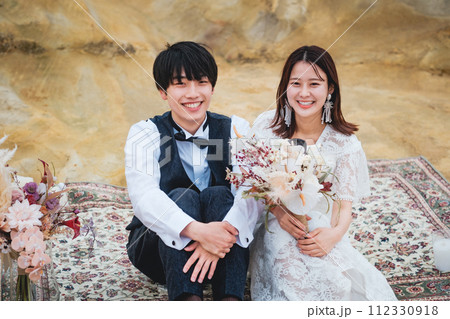 隣り合わせで岩場で座ってる新郎新婦 隣り合わせで岩場で座ってる新郎新婦 112330918