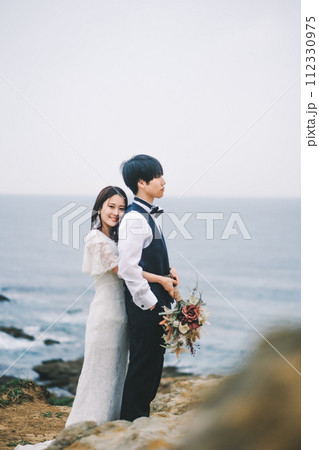 海岸で寄り添う新郎新婦 112330975