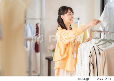 アパレルショップでタブレットを操作しながら働くミドルの女性の店員 112331214