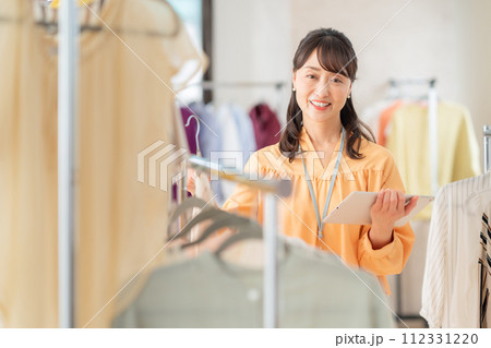 アパレルショップでタブレットを操作しながら働くミドルの女性の店員 アパレルショップでタブレットを操作しながら働くミドルの女性の店員 112331220