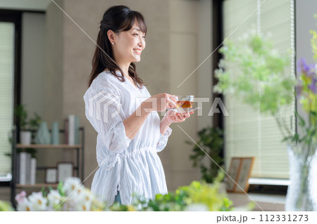 リビングの窓際で紅茶を飲むミドルの女性 112331273