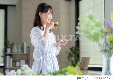 リビングの窓際で紅茶を飲むミドルの女性 112331275