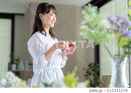 リビングの窓際で紅茶を飲むミドルの女性 112331276