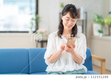 リビングでスマホを操作するミドルの女性 リビングでスマホを操作するミドルの女性 112331289