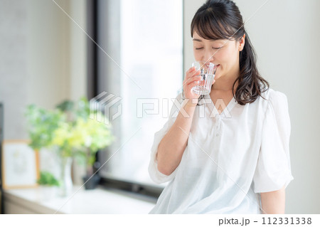 リビングで水を飲むミドルの女性 リビングで水を飲むミドルの女性 112331338