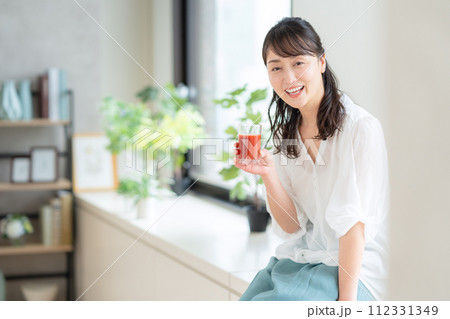 リビングでトマトジュースを飲むミドルの女性 112331349