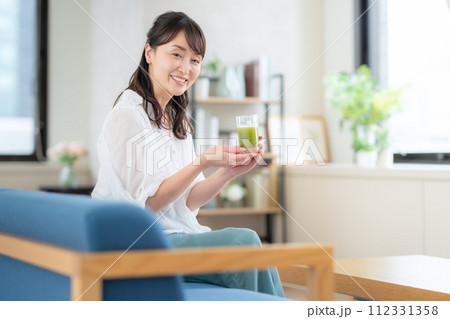 リビングで青汁を飲むミドルの女性 112331358