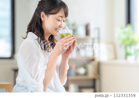 リビングで青汁を飲むミドルの女性 リビングで青汁を飲むミドルの女性 112331359