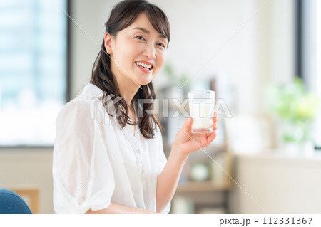 リビングで牛乳を飲むミドルの女性 リビングで牛乳を飲むミドルの女性 112331367