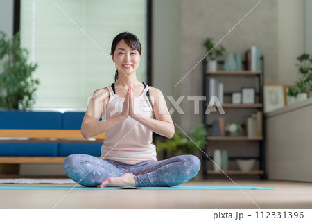 リビングでヨガをするミドルの女性 リビングでヨガをするミドルの女性 112331396