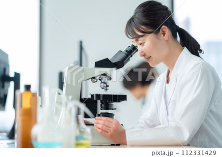 顕微鏡を覗いて研究、実験をするミドルの女性 112331429