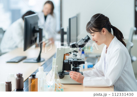 顕微鏡を覗いて研究、実験をするミドルの女性 112331430