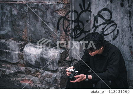 座って撮った写真を確認する男性 112331566