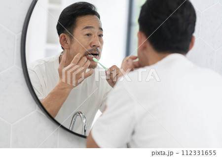 歯磨きをしながら歯茎を気にする50代の男性 112331655
