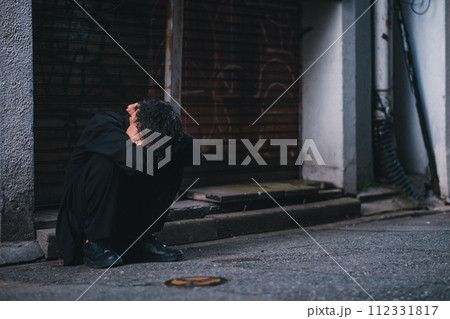 裏路地に座り込む男性 112331817