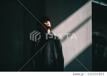 光が差し込む壁の前に立つ男性 112331921