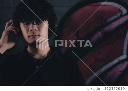 高架下でヘッドフォンをつけてる男性 高架下でヘッドフォンをつけてる男性 112332019