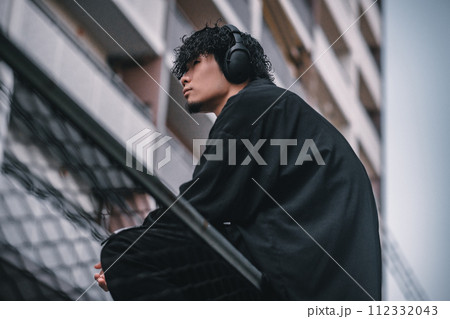 街で待ち合わせをするヘッドフォンをしたオシャレな男性 112332043