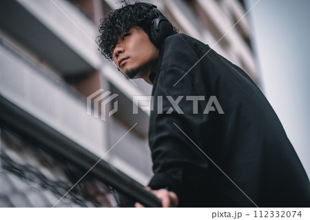街で待ち合わせをするヘッドフォンをしたオシャレな男性 112332074