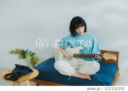 リビングでギターを弾く女性 112332191
