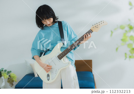 リビングでギターを弾く女性 112332213