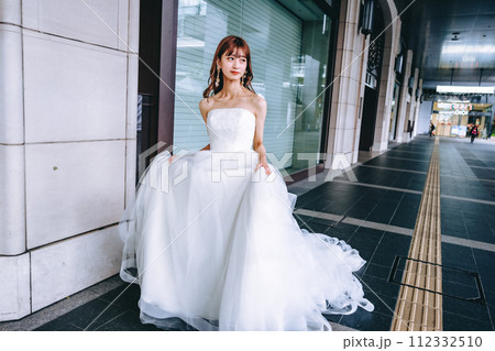 街をウエディングドレスを持って歩く花嫁 街をウエディングドレスを持って歩く花嫁 112332510