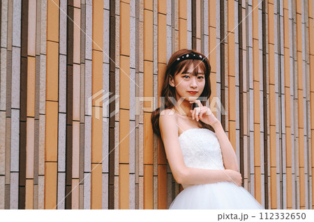 カラフルな壁の前でポージングするウエディングドレスを着た花嫁 112332650