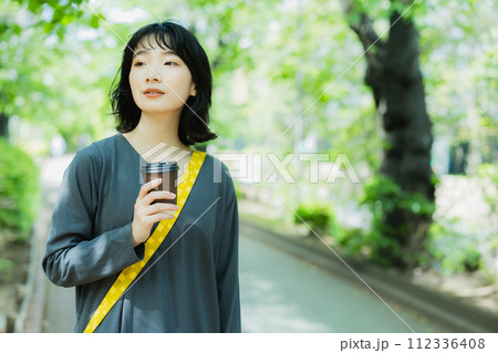 コーヒーを片手に散歩する女性 コーヒーを片手に散歩する女性 112336408