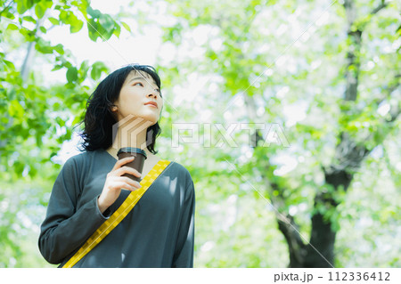 コーヒーを片手に散歩する女性 コーヒーを片手に散歩する女性 112336412