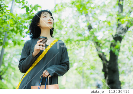 コーヒーを片手に散歩する女性 コーヒーを片手に散歩する女性 112336413