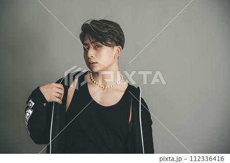 グレーバックの背景で上着を羽織っている男性 112336416