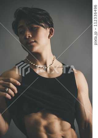 タンクトップを捲り上げて腹筋を見せる若い男性 タンクトップを捲り上げて腹筋を見せる若い男性 112336496