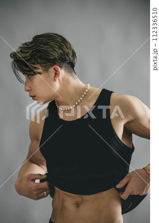 タンクトップを捲り上げて腹筋を見せる若い男性 タンクトップを捲り上げて腹筋を見せる若い男性 112336510