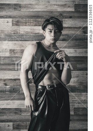 木目の背景でタンクトップを着ている筋肉質の若い男性 112336605