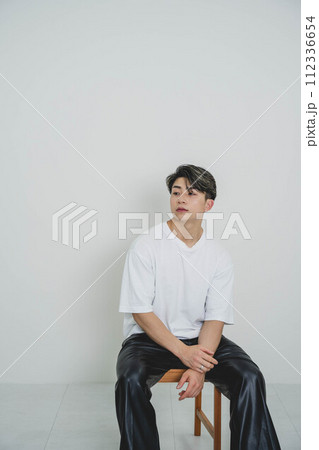白いTシャツを着て椅子に座っている若い男性 112336654