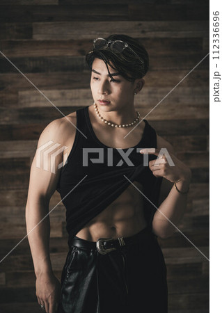 木目の背景に立つ黒いタンクトップで筋肉質の若い男性 112336696