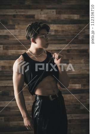 木目の背景に立つ黒いタンクトップで筋肉質の若い男性 木目の背景に立つ黒いタンクトップで筋肉質の若い男性 112336710