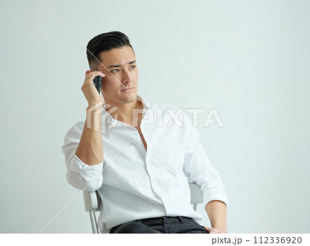 椅子に座って電話をする男性 椅子に座って電話をする男性 112336920