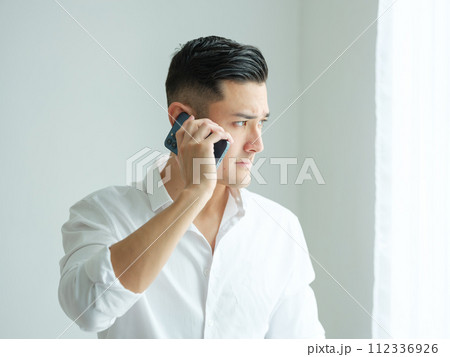 窓際で電話をする男性 112336926