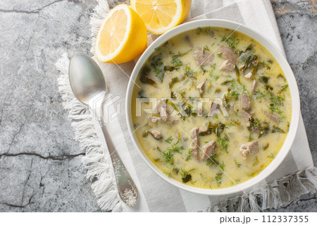 Magiritsa Greek Easter soup with lamb intestines and liver, herbs, seasoned with egg and lemon sauce close-up in a bowl. Horizontal top view 112337355